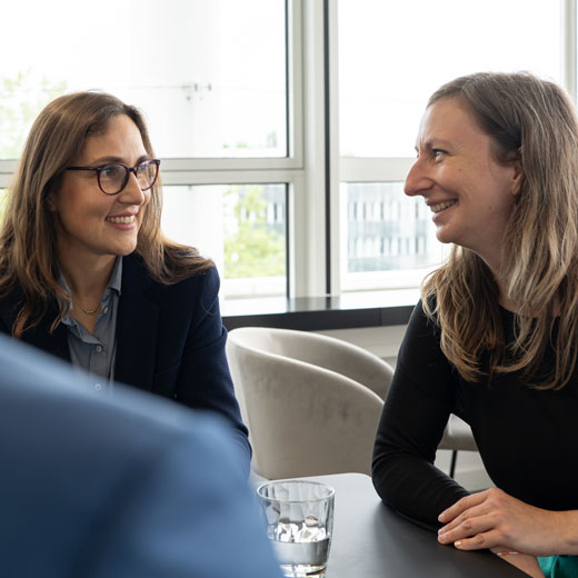 Zwei Frauen im beruflichen Kontext, in einem entspannten Gespräch miteinander